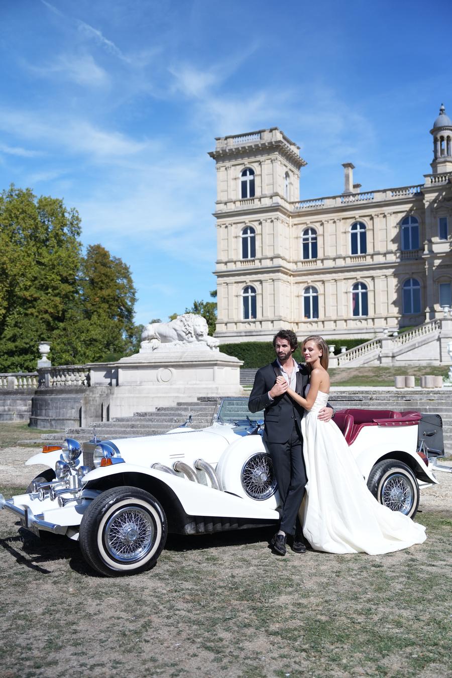 Les mariés main dans la main devant le château et sa voiture ancienne, lors d'une séance couple